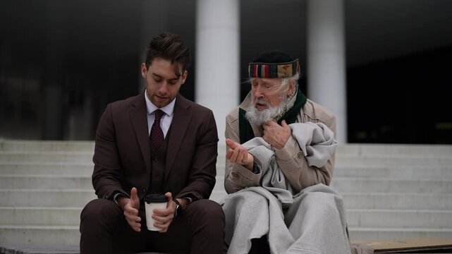 Kind businessman in suit giving takeaway coffee to homeless elderly man, showing compassion and generosity in urban environment. Compassionate business man sharing takeaway coffee outdoors.