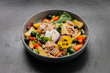 Gourmet salad bowl with tuna, poached egg, colorful vegetables, and edible flower garnish