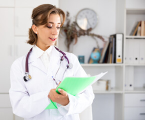 Woman doctor wear white medical uniform and stethoscope with folder of documents in clinic