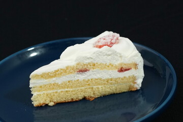 One small Japanese strawberry shortcake on a stylish Japanese plate on a black cloth on a white table