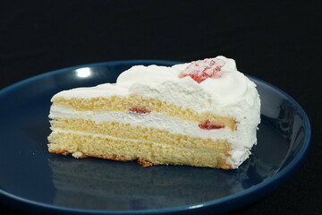 One small Japanese strawberry shortcake on a stylish Japanese plate on a black cloth on a white table