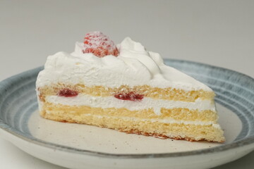 One small Japanese strawberry shortcake on a stylish Japanese plate on a white table