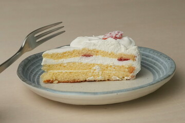 Japanese strawberry shortcake and fork on each stylish large and small plate on a wooden table