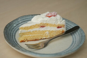Japanese strawberry shortcake and fork on each stylish large and small plate on a wooden table