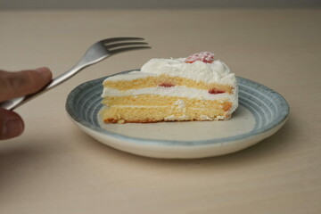 Japanese strawberry shortcake and fork on each stylish large and small plate on a wooden table