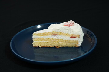 One small Japanese strawberry shortcake on a stylish Japanese plate on a black cloth on a white table