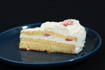 One small Japanese strawberry shortcake on a stylish Japanese plate on a black cloth on a white table