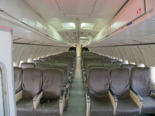 View of empty passenger seating area of an old 737-200 airplane from the front of the plane