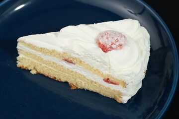One small Japanese strawberry shortcake on a stylish Japanese plate on a black cloth on a white table