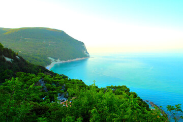 Splendid view from Piazzale Marino in Sirolo at the vast balmy mirror-like expanses of the Adriatic Sea skimming the momentous Mount Conero cliff with its thriving vegetation and green surroundings