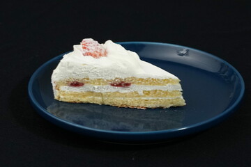 One small Japanese strawberry shortcake on a stylish Japanese plate on a black cloth on a white table