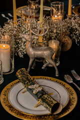 Holiday table with candles, plates, and New Year decorations in a cozy dinner