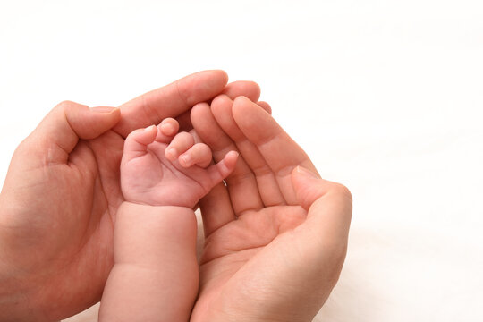赤ちゃんの手を優しく包み込むママの手