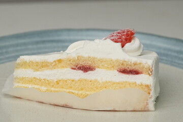 One small Japanese strawberry shortcake on a stylish Japanese plate on a white table