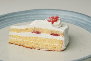 One small Japanese strawberry shortcake on a stylish large plate on a white table