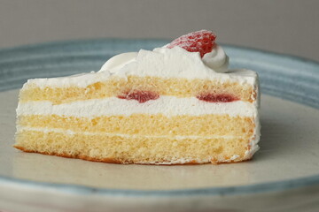 One small Japanese strawberry shortcake on a stylish large plate on a white table