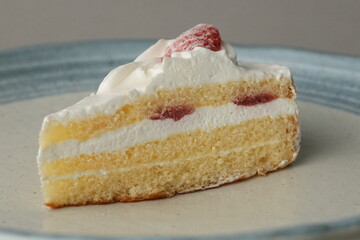 One small Japanese strawberry shortcake on a stylish large plate on a white table