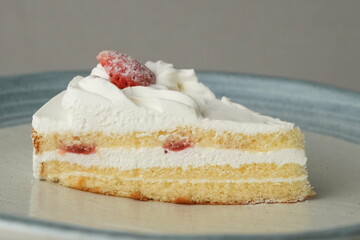 One small Japanese strawberry shortcake on a stylish large plate on a white table