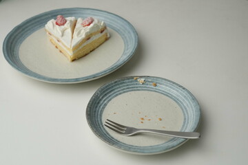 Two Japanese strawberry shortcakes on a stylish large plate on a white table and a small plate after eating them