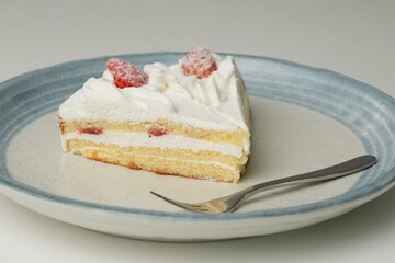 Two Japanese strawberry shortcakes and a large fork on a stylish large plate on a white table