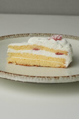 One small Japanese strawberry shortcake on a stylish large plate on a white table