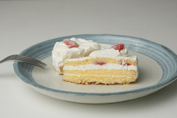 Two Japanese strawberry shortcakes and a large fork on a stylish large plate on a white table