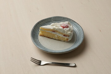 Japanese strawberry shortcake and fork on each stylish large and small plate on a wooden table