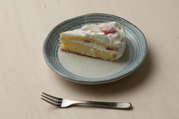 Japanese strawberry shortcake and fork on each stylish large and small plate on a wooden table