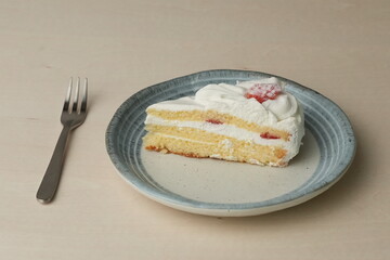 Japanese strawberry shortcake and fork on each stylish large and small plate on a wooden table