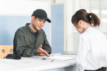 自動車整備工場の受付で説明・見積もり・提案をする整備士の男性と顧客の女性
