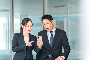 スマホ・スマートフォンを見てショック・驚く会社員（炎上・トラブル・失敗・カスハラ・困る）
