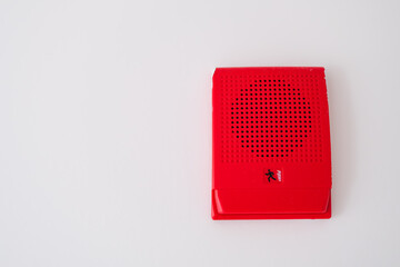 red fire alarm speaker mounted on a white wall, designed to alert occupants during emergencies with a visual and auditory signal for enhanced safety and quick evacuation.