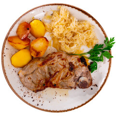 Grilled pork chop served with roasted potatoes and tangy sauerkraut garnished with parsley. Isolated over white background