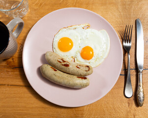 Delicious fried eggs with sausage served on platter for breakfast