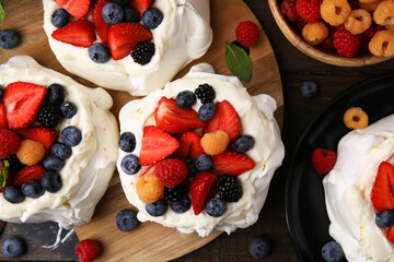 Pavlova cake (meringue dessert) with whipped cream and fresh berries on wooden table, flat lay