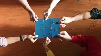 Top down view of skilled business people assemble blue jigsaw puzzle on meeting table. Group of diverse team working together to solve the puzzle. Represented togetherness, cooperative. Convocation.