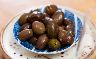 Large green olives with pits served to table in bowl