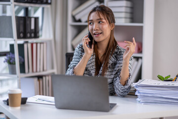 Obraz premium Asian business woman using calculator and laptop for doing math finance call phone at the office desk, tax, report, accounting, statistics, and analytical research concept.