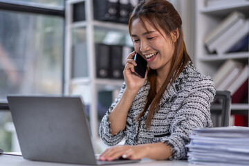 Asian business woman using calculator and laptop for doing math finance call phone at the office desk, tax, report, accounting, statistics, and analytical research concept.