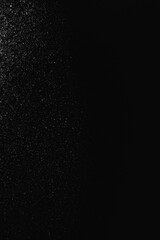 Close-up of scattered small snowflakes on a dark surface, creating a misty, abstract texture in low light. Captures a moody, atmospheric effect.
