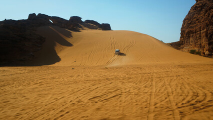 Van driving up dune in Saudi Arabia - wide shot