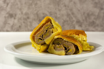 Bolen Pisang is a light dish made from bananas covered in rolled sheets of pastry dough. Various toppings such as cheese and chocolate. Served in white plate on white background. Selective focus image