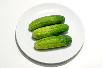 Green cucumber on white plate isolated on white background. Green cucumbers texture template arranged and harvested