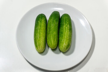 Green cucumber on white plate isolated on white background. Green cucumbers texture template arranged and harvested