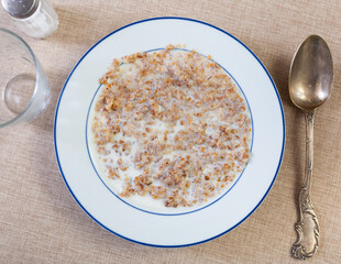 Appetizing milk oatmeal porridge served on plate for breakfast