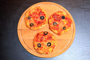 Three small pizzas with olives and cheese on wooden board