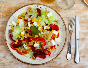 Appetizing salad of fresh vegetables served with feta cheese and pesto on plate