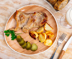 Appetizing piece of fried pork with marinated cucumber and potatoes served on plate