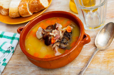 Appetizing pea soup with smoked meat and vegetables served in bowl