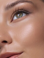 Fototapeta premium Extreme close-up of a woman's eye with long lashes and perfectly applied natural makeup, highlighting her flawless skin and glowing complexion. Ideal for beauty, makeup, and skincare advertisements.